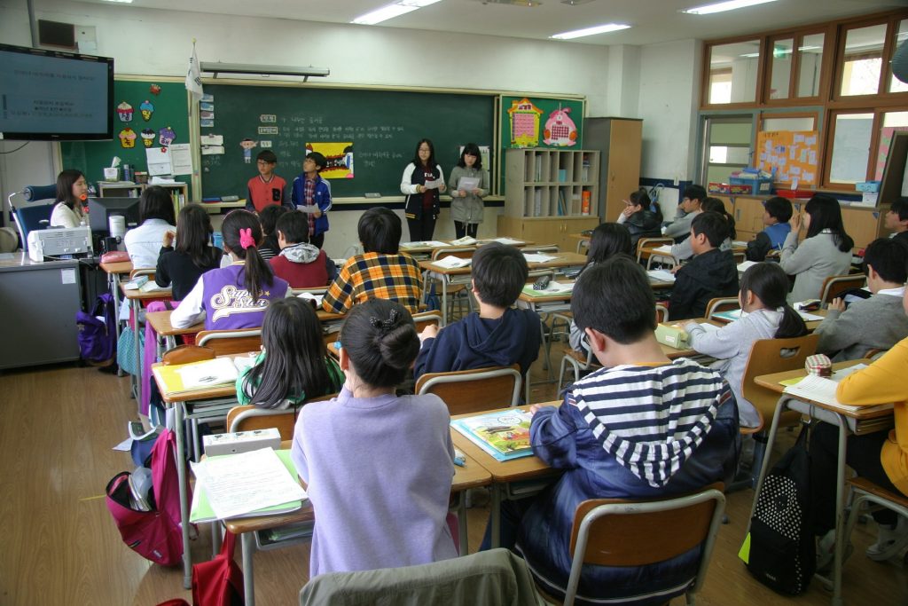four children speaking in front of a class room